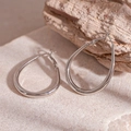 Primo piano di orecchini a goccia in argento lucido su superficie in pietra naturale con macro - Argento