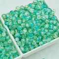 Detailed view of turquoise 6mm cracked glass beads in a tray for DIY jewelry making - 6mm / Green Blue