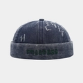 Detail of distressed navy denim docker hat with green 3D embroidery showing PROGRESS text - Adjustable / Navy Blue