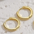 Detaillierte Makroansicht vergoldeter Creolen mit Zirkonia-Besatz auf strukturiertem Stein - 15MM Zirkonia Creolen / Gold