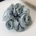 Detailed texture of dusty blue organza scrunchie with soft pleated floral design - Green