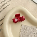 Detail of red acetate bow hair claw with gold lettering on a minimalist tray - Red