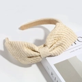 Detailed view of a beige woven straw headband featuring a large stylish bow decoration - Beige