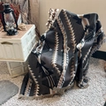 Detail of bohemian geometric knit blanket with tassels in an outdoor camping setup - XT2022-37 (Black Brown Totem)