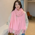 Close-up of soft pink scarf with fringe details worn by a model in a natural setting - Pink