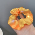 Detailed view of an orange satin LED scrunchie showing glowing light beads on silk fabric - Bright Yellow
