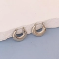 Vue rapprochée de créoles torsadées en argent avec une finition polie sur pierre - Créoles Sculpturales Torsadées Argent