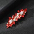 Détail d'une pince à cheveux avec strass rouges et perles sur fond noir texturé - Modèle Pierre Rouge / Or