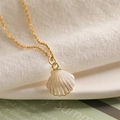 Detailed close-up of golden shell pendant with pearlescent finish on soft white fabric - Shell Pearlescent Style / White