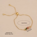 Goldenes Schiebearmband mit grünen, roten und pinken Glasanhängern in Herzform - Armband