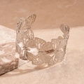 Detail einer silbernen Armspange mit durchbrochenem Schmetterlings-Design auf Stein - Hohl Schmetterling Offene Manschette / Silber