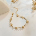Pulsera de doble capa dorada con corazones y cuentas de cristal sobre fondo blanco - Dorado