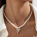 Close-up of a pearl necklace with a silver bow pendant on a model's neck - Silver Bow Pendant Pearl Necklace