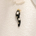Elegant black horn charm with gold trim and white star patterns on a beige surface - Black with Stars