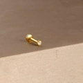 Gedetailleerde macro van gouden labret piercing met een glanzende zirkonia steen - Gouden Enkele Zirkonia Stijl 1