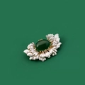 Elegant flower brooch with green gemstone center and silver petals on dark background - Begonia Flower