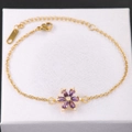 Detalle macro de la pulsera dorada con pétalos de flores púrpuras y circonitas - Flor Púrpura