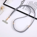Adjustable gray nylon phone lanyard with gold metal hardware and connector pad on white desk - Gray