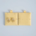 Macro detail of gold flower earrings with white pearls on yellow velvet display cards - Yellow