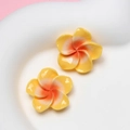 Detailed view of yellow and orange resin frangipani flower charms for DIY accessories - Small Yellow
