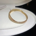 Close-up of a double-layered gold pavé zircon flower open bangle in a white jewelry box - Gold