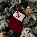 Red knit Christmas stocking with embroidered letter N and mini hat on tree branch - Style N