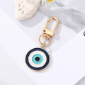 Detailed view of blue evil eye charm with gold spring clasp on a floral background - 5 Black Blue Round Eye