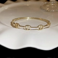 Gros plan du bracelet à maillons dorés serti de zircons brillants sur une assiette blanche - Or (Plaqué Or Véritable)