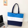 Detail of a three-color spliced canvas tote bag with blue panels on a desk - Blue