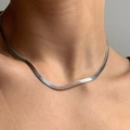 Close-up of a sleek silver snake chain necklace worn on a woman's collarbone - Steel Color Herringbone Flat Chain