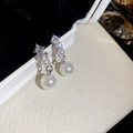Detailaufnahme der silbernen Ohrringe mit Diamantbesatz und Perlen in einer Schmuckschachtel - Silbernadel-Ohrringe - Silber - Beige