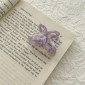 Detail shot of purple marble acetate butterfly hair claw on a vintage book page - Purple