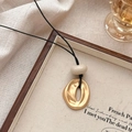 Ketting met onregelmatige gouden ovale hanger en beige kraal op houten dienblad - Goud