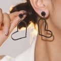 Elegant black heart earrings with sparkling crystals and floral stud detail on model - Black Hollow Heart Sunflower Style (DTE1516133GU-BK)