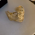 Close-up of golden hollow leaf texture on a wide adjustable metal cuff bracelet - Gold Hollow Leaf Texture Style