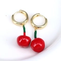 Detalle de los pendientes de cereza roja esmaltada en un plato blanco con aros dorados - Forma de Cereza