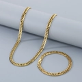 Conjunto de collar y pulsera de cadena cubana dorada de acero sobre un pedestal gris - Conjunto Dorado 7mm