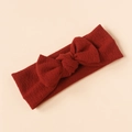 Detailed top view of red ribbed knit baby headband with 3D bow on a beige background - Red