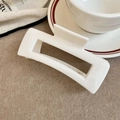 Close-up of minimalist white rectangular hair claw clip on soft beige textured fabric - White