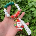 Detail of Christmas beaded keychain with Santa pendant and tassel held outdoors - Style 9 (Flat Santa Claus Pendant)