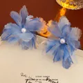 Pendientes de flores de malla azul con perla blanca sobre tablero beige texturizado - Pendientes / Azul