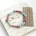 Minimalist crystal bracelet with pastel pink and light blue beads on a stone surface - Red Wood Grain Texture Bracelet