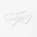 Macro shot of two white alloy heart flame pendants for minimalist DIY jewelry making - White