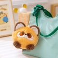 Porte-clés panda en peluche roux avec clip vert suspendu sur un sac en toile deco - Raton laveur