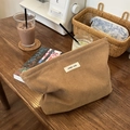Detail of khaki corduroy makeup bag texture with simple wish label on wooden table - Camel