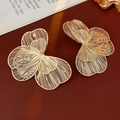Dettaglio orecchini a fiore traforati dorati su elegante sfondo in pelle rossa scura - Oro - Grande