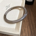 Macro shot of minimalist taupe resin bangle with a polished marble-like finish - Gray