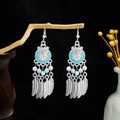 Detail of silver bohemian tassel earrings with blue beads hanging on a wooden branch - E6100-27 Feather Bead