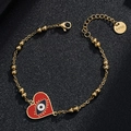 Detail of gold-plated stainless steel evil eye heart charm bracelet on black background - Style 10 (Red Heart)