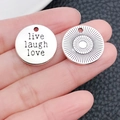Detailansicht der silbernen Anhänger mit Live-Laugh-Love-Gravur auf der Hand - Runder Livelaughlove Buchstabenanhänger (5028)
